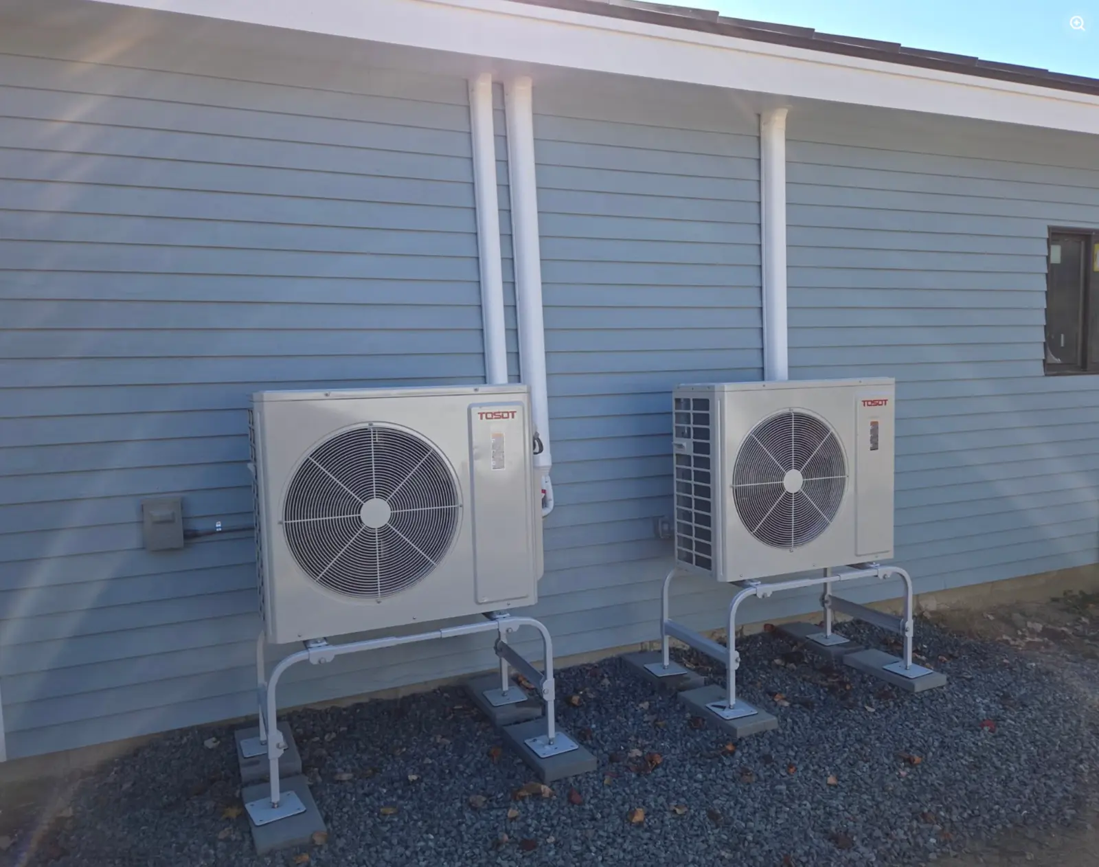 Two outdoor ductless heating and cooling units installed beside a home